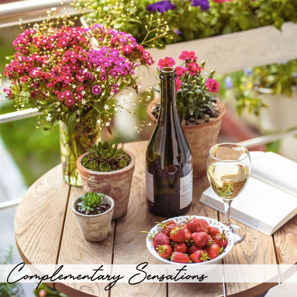 A bottle of Burgundy wine on a table next to a vase of flowers.