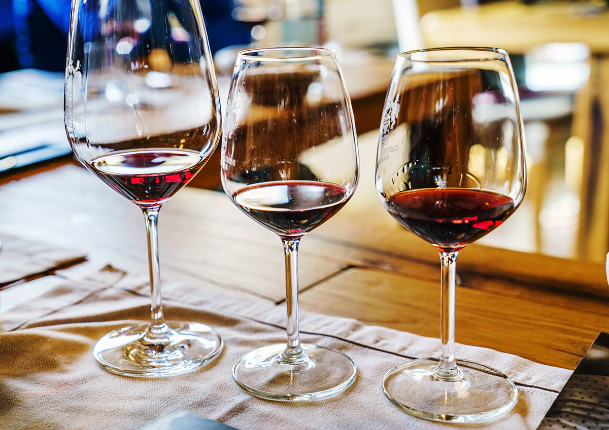 Three wine glasses each with small amounts of Burgundy wine for tasting.