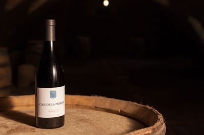 A bottle of Clos de la Perriere sitting atop a barrel. 