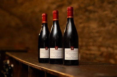 Three bottles of Jean Merechal Mercurey wine lined up diagonally on a wooden table. 