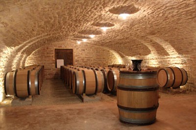 Barrels of Saint-Veran wine in a beautifully-lit stone cellar. 